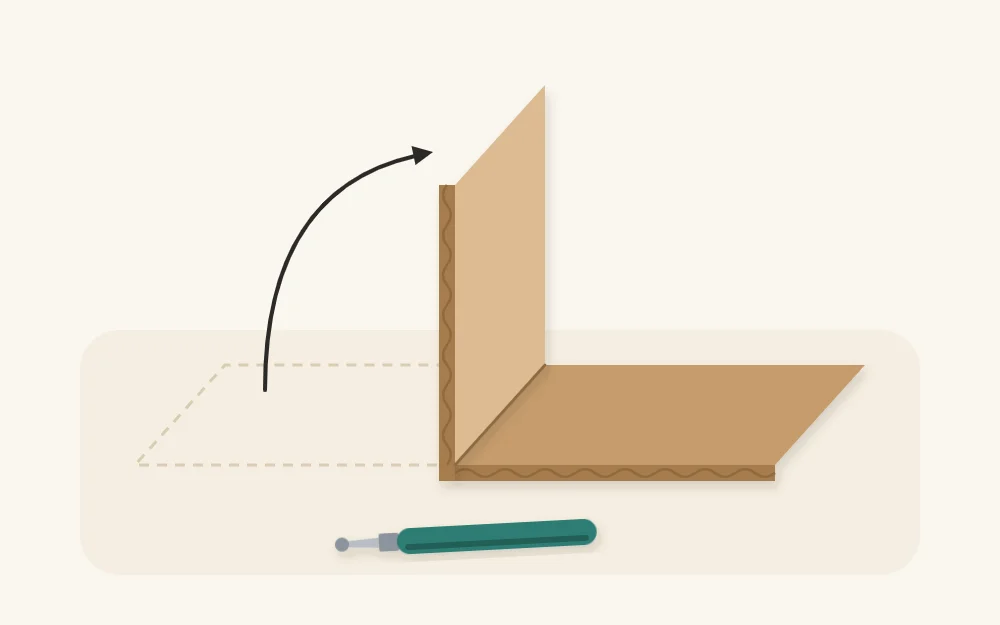Cardboard strip folded up along a scored line into a right angle beside a blunt scoring tool