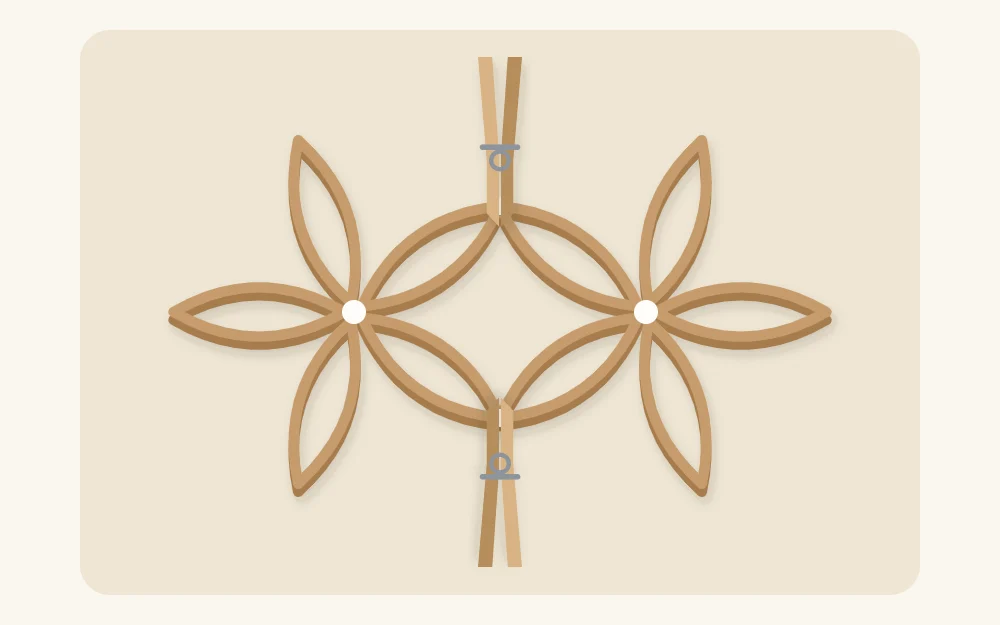 Two paper tube flower shapes joined with clothespins holding the glued points while they dry