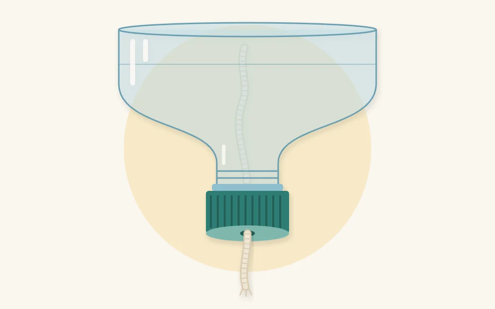 An upside-down bottle top with a cotton string wick threaded through a hole in the cap